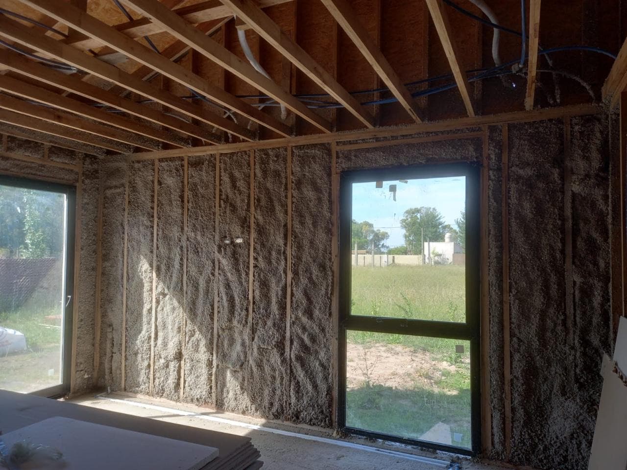 Pared con celulosa proyectada junto a ventana, obra de Tandil